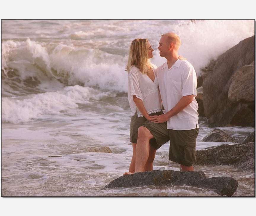 couple un-nerved waves crashing behind | engagement photos